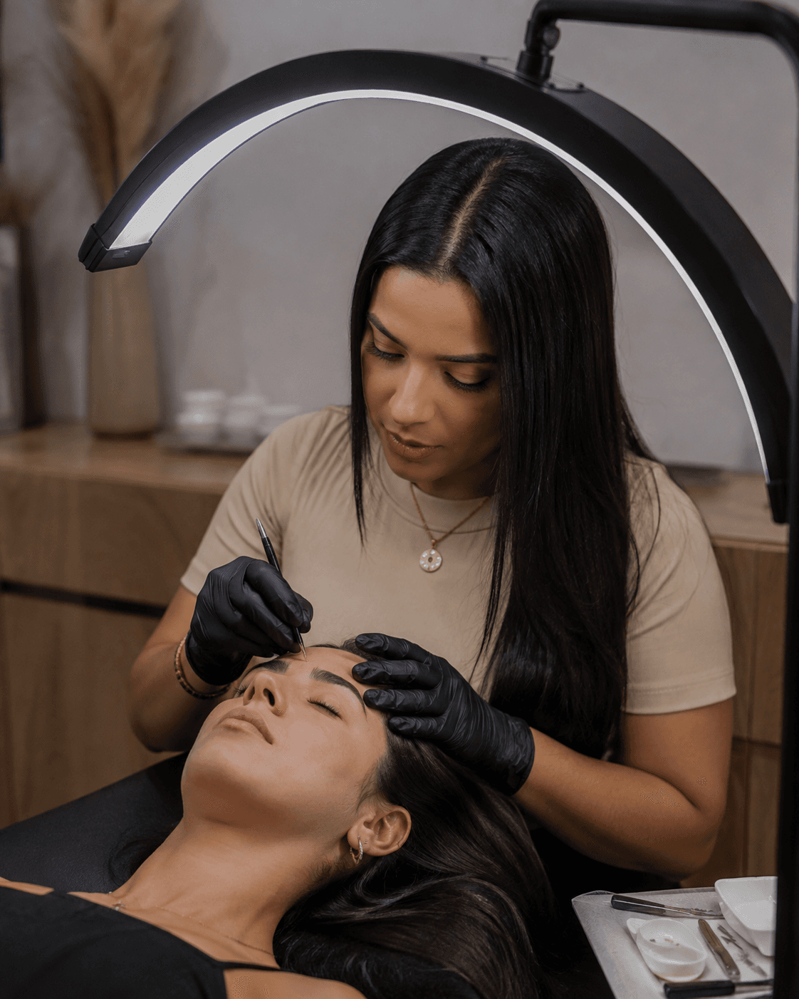 Profissional realizando design de sobrancelhas em uma cliente